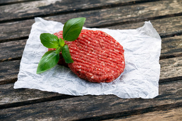 Home HandMade Minced Beef burgers decorated with Basil. on crumpled paper. wooden table.