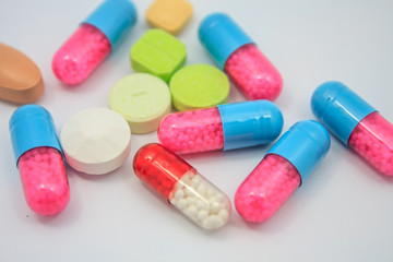 Colored pills, tablets and capsules on white background