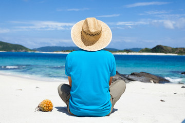 Fototapeta na wymiar Man sitting on a deserted tropical island beach, Okinawa, Japan