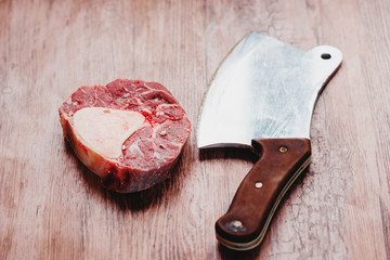 raw meat with the sacking on a wooden background with knife and ax