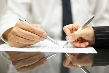 Business man is showing with pen to business woman where to sign