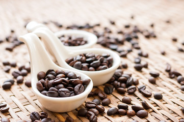 Coffee Beans in white spoon on wooden background