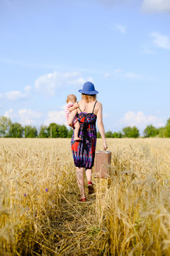 Young mother travelling with her child on hand on the wheat