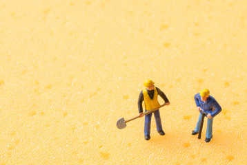 miniature people on yellow sponge background