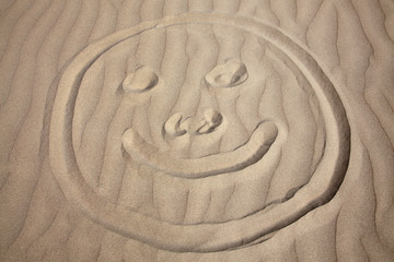Fototapeta na wymiar Background of a smiley face drawing on a coastline sand beach
