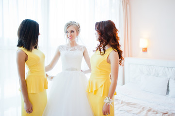 Naklejka premium gentle blonde bride with bridesmaids at yellow dress