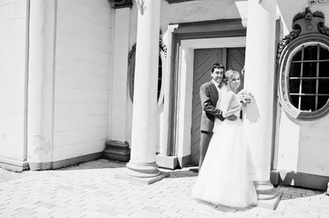 wedding couple near white stone wall with columns