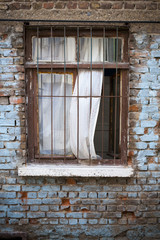 Ventana abierta con cortinas en pared de ladrillos antigua