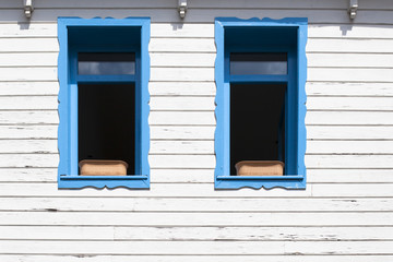 Fachada blanca de madera con ventanas azules