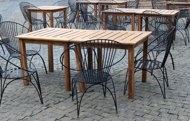 wood tables and black chairs set up for lunch outside cafe