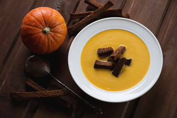 Pumpkin cream-soup with croutons on a dark wooden background