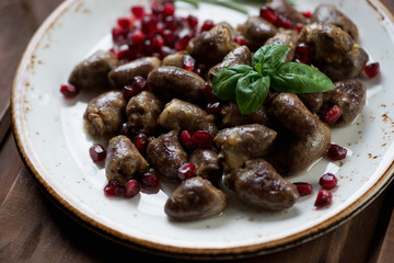 Roasted chicken hearts with pomegranate seeds, close-up