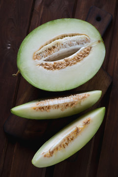Above view of sliced cantaloupe melon, dark brown wooden surface