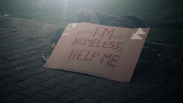Homeless beggar sleeping on the street, adult man begging down on pavement
