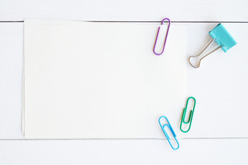 Blank note papers and colorful clips on white wood background