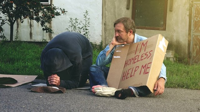 Man taking money from homeless beggars and walking away