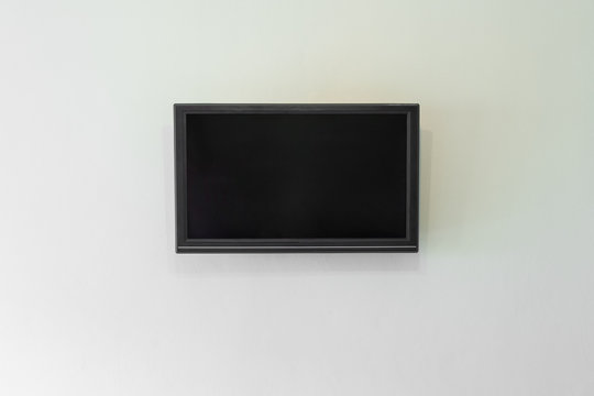 Black LCD or LED tv screen hanging on a wall background