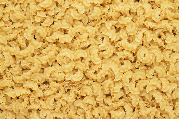 dry uncooked creste di galli pasta texture background