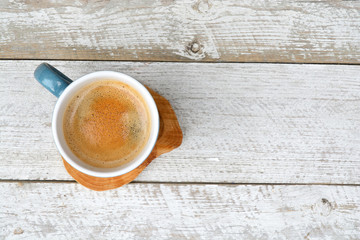 Old white wooden shelves background with a blue coffee cup with coffee cream