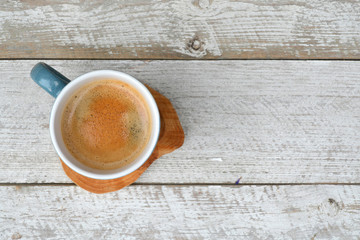 Old white wooden shelves background with a blue coffee cup with coffee cream