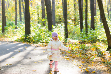 Happy kid girl having fun the autumn park.