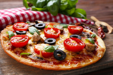 Tasty pizza with vegetables and basil on table close up