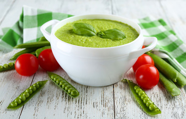 Tasty peas soup and cherry tomatoes on table close up