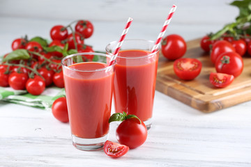 Glasses of tomato juice with vegetables on wooden table close up