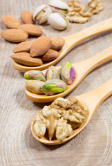 Almonds, walnuts and pistachio on a wooden spoon.