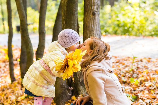 Mother kissing her daughter in the park.  Woman with child on