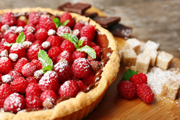 Tart with fresh raspberries, on wooden background