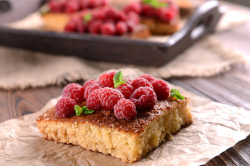 Fresh pie with raspberry on parchment on wooden table, closeup