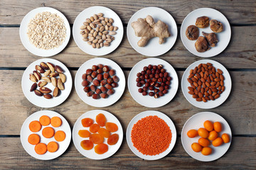 Different products on saucers on wooden table, top view