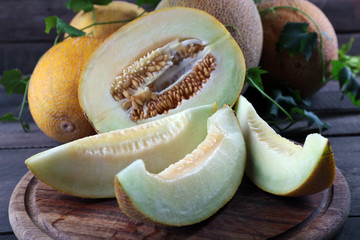 Ripe melons with green leaves on wooden table close up