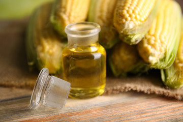 Fresh corn with bottle of oil on table close up