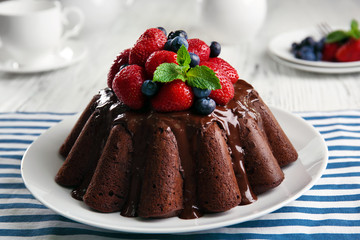 Delicious chocolate cake with strawberries in plate on table, closeup