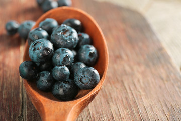 Fresh blueberries in spoon on wooden table close up
