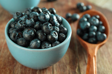 Fresh blueberries in spoon and bowl on table close up