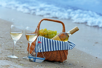 Picnic basket with bottle of wine on sand beach