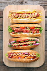 Fresh hot dogs on cutting board on wooden background