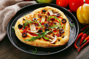 Heart shaped pizza on metal tray on wooden background