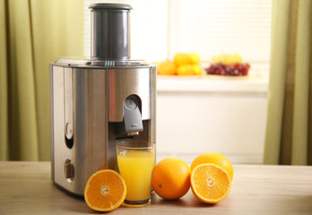 Juicer and orange juice on kitchen table