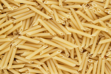 dry uncooked penne lisce pasta texture background