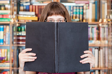 girl reads big book in library