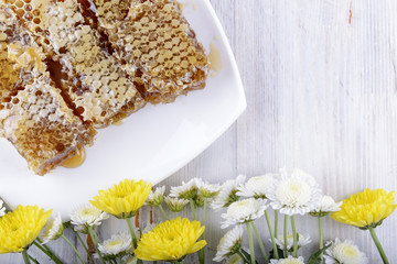 honeycombs and flowers on white wooden background
