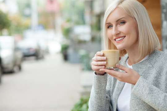 Attractive blond girl is relaxing with mug of latte
