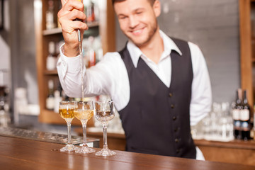 Handsome male bartender is making alcohol beverage