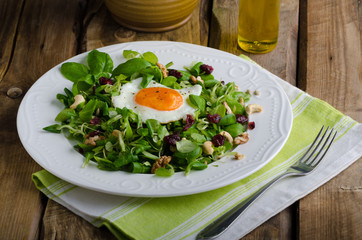 Fresh salad with nuts, raisins and fried egg