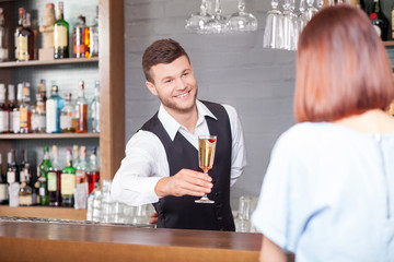 Cheerful male bartender is serving customer in bar