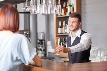 Handsome young barman is receiving order from customer
